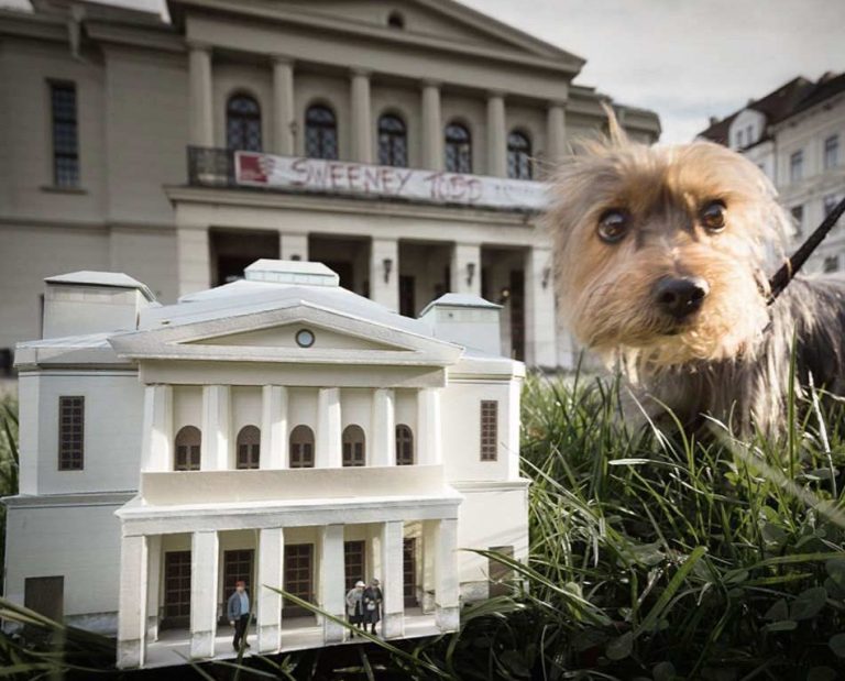 Papiermodell im Vordergrund auf grünem Gras und Oper Görlitz im Hintergrund als Papierkunstwerk.