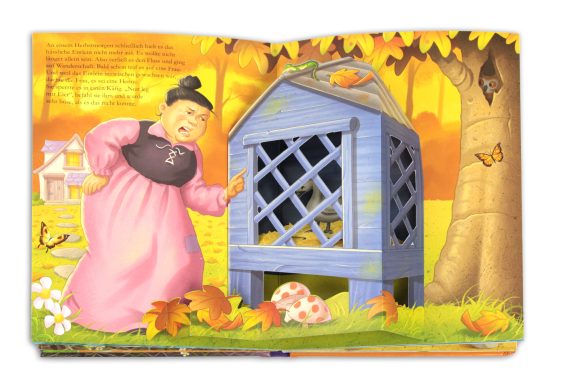 Eine Frau in einem rosa Kleid steht neben einem blauen Käfig unter bunten Herbstblättern.