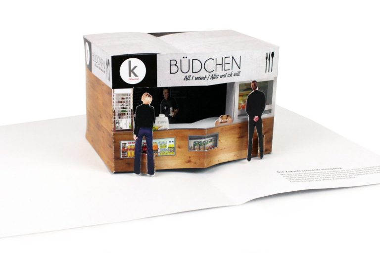 Stilisiertes Essensstandmodell aus Papier mit zwei Figuren und dem Namen "BÜDCHEN".