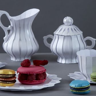 Hübsches Service aus Papier mit bunten Macarons aus Papier auf einem Tisch.