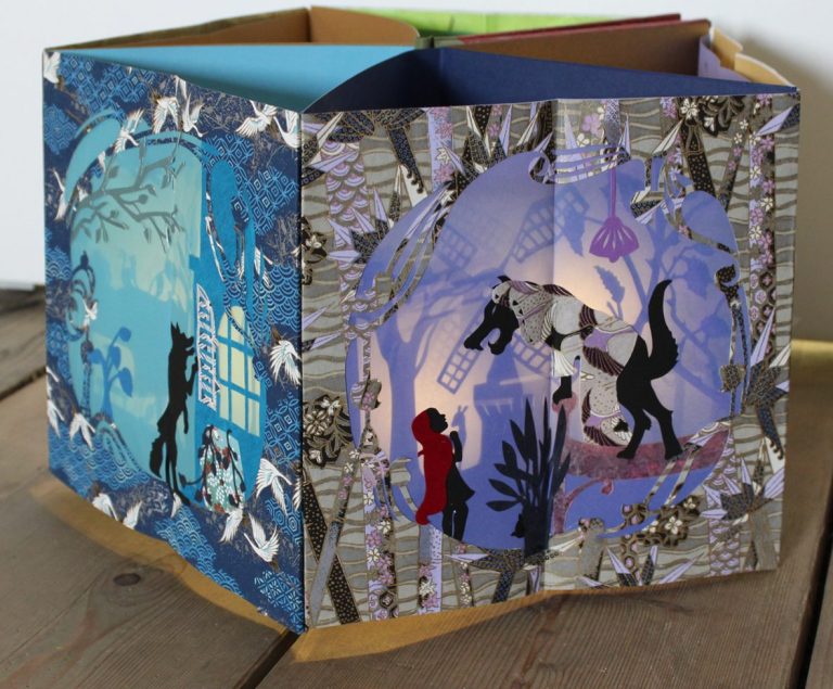 Stilisiertes Essensstandmodell aus Papier mit zwei Figuren und dem Namen "BÜDCHEN".