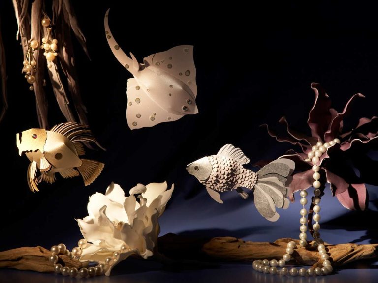 Fantastische Meereslebewesen, darunter Papierfische und Stachelrochen, vor dunklem Hintergrund.