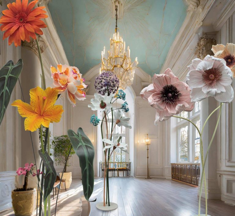 Bunte große Papierblumen in einem eleganten Raum mit einer hohen Decke.