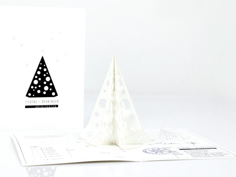 Weißer, gefalteter Weihnachtsbaum aus Papier mit Lochmuster auf einer Grußkarte