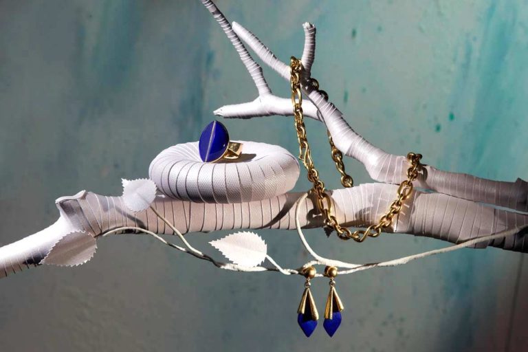 Goldschmuck präsentiert auf einem Zweig aus Papier mit Blätten aus Papier.