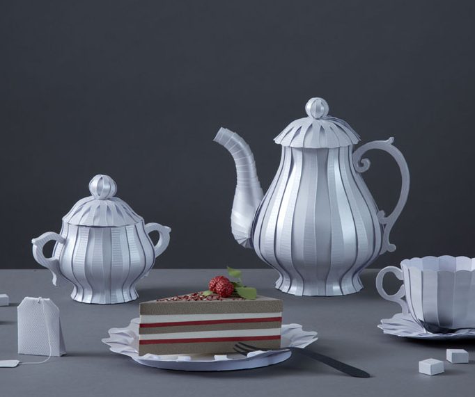 Silbernes Teeservice aus Papier mit einer Torte auf einem Teller, dekoriert mit Himbeeren aus Papier.