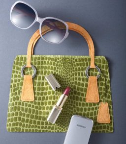 Handtasche aus Papier genäht mit Orangefarbenen Griffen, Sonnenbrille, Lippenstift und Smartphone.