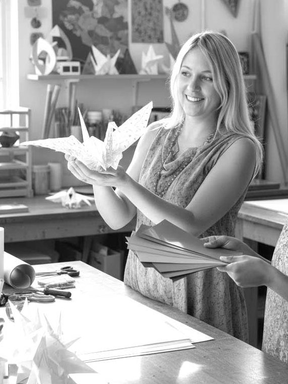 Julia Schreiber hält einen Origami-Kranich in ihrem Atelier.