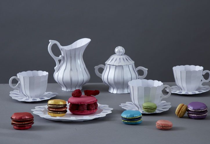 Papiergeschirr in weiß mit bunten Süßigkeiten aus Papier auf einem Tisch.